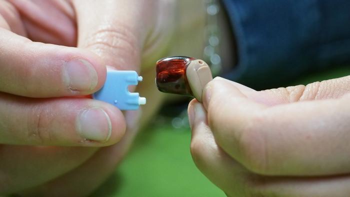 Ein Im-Ohr-Hörgerät mit rotem Gehäuse wird gereinigt